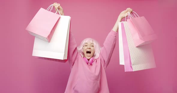 Happy Girl Enjoys After Shopping with Colorful Bags in Pink Colour Concept alt