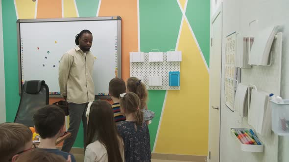 An African American Teacher Teaches a Group of Children 1012 Years Old Studying Animals and Fruits alt