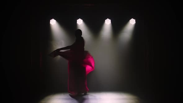 Silhouette a Young Girl Dancer in a Red Sari. Indian Folk Dance. Shot in a Dark Studio with Smoke alt