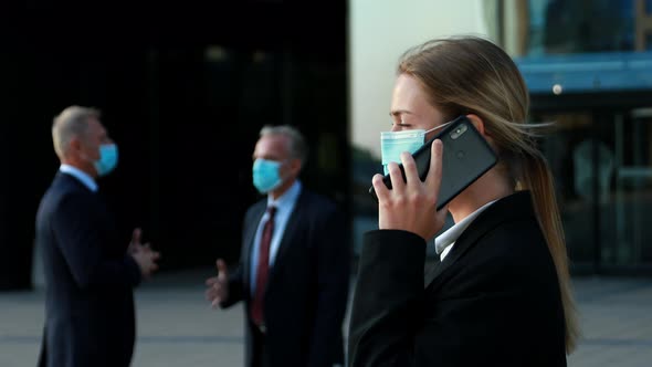 Business Woman in Protective Face Masks Gives Instructions To Subordinates on the Phone Team