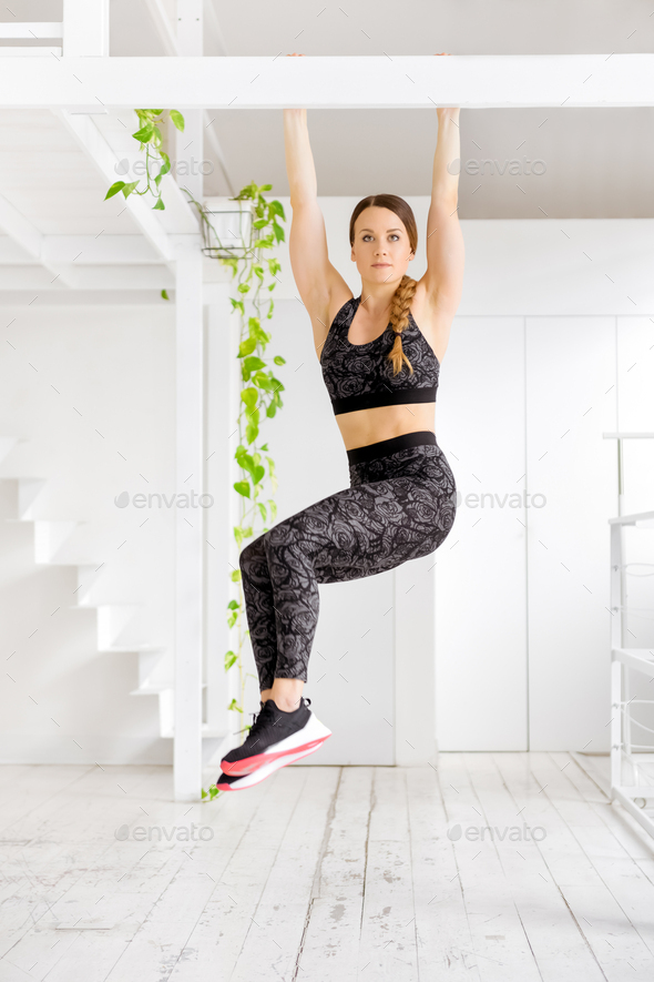 Woman working out doing a toes to bar exercise - Stock Photo - Images
