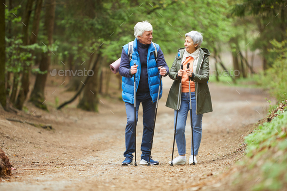 Cheerful Senior Couple Enjoying Nordic Walk in Forest