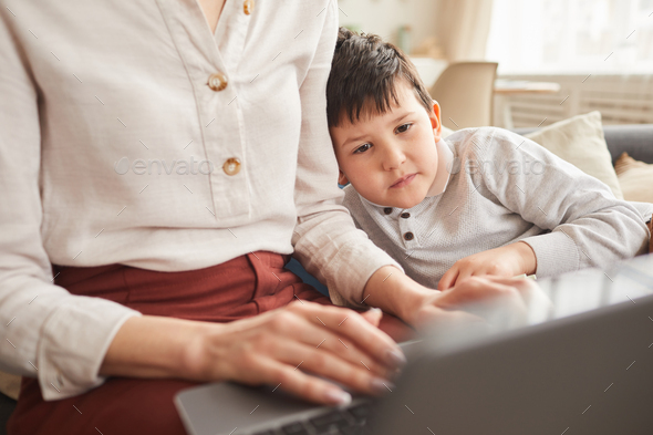 Cute Boy Looking at Laptop Screen while Mom Working at Home