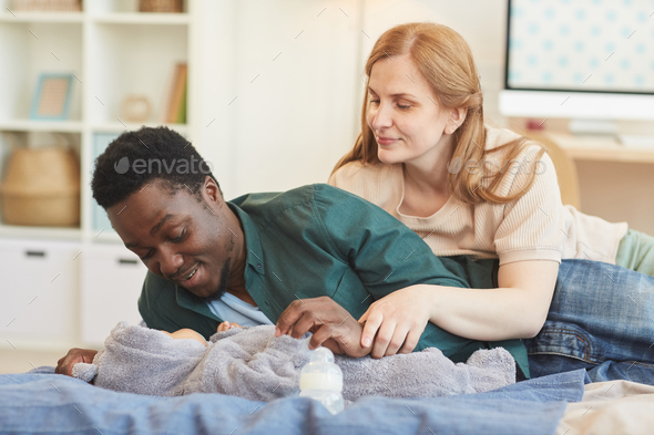 Modern Interracial Family Playing with Baby on Bed