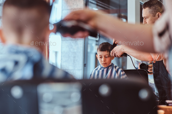 Little pretty school boy had his first trendy haircut at modern barbershop