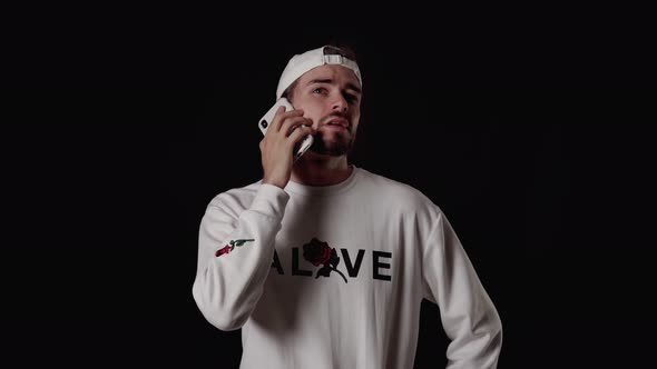 Trendy 20s Man answering mobile phone, talking, wide, black background alt