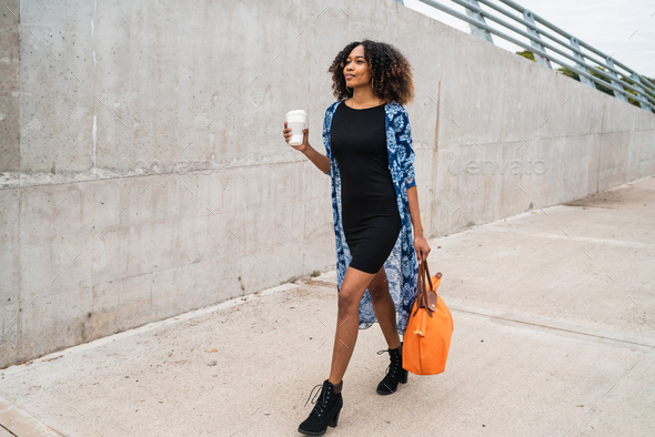 Afro american woman walking with coffee.