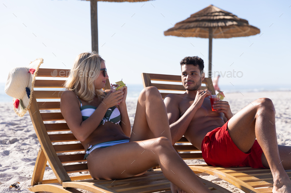 Caucasian couple sitting on deck chairs at the beach