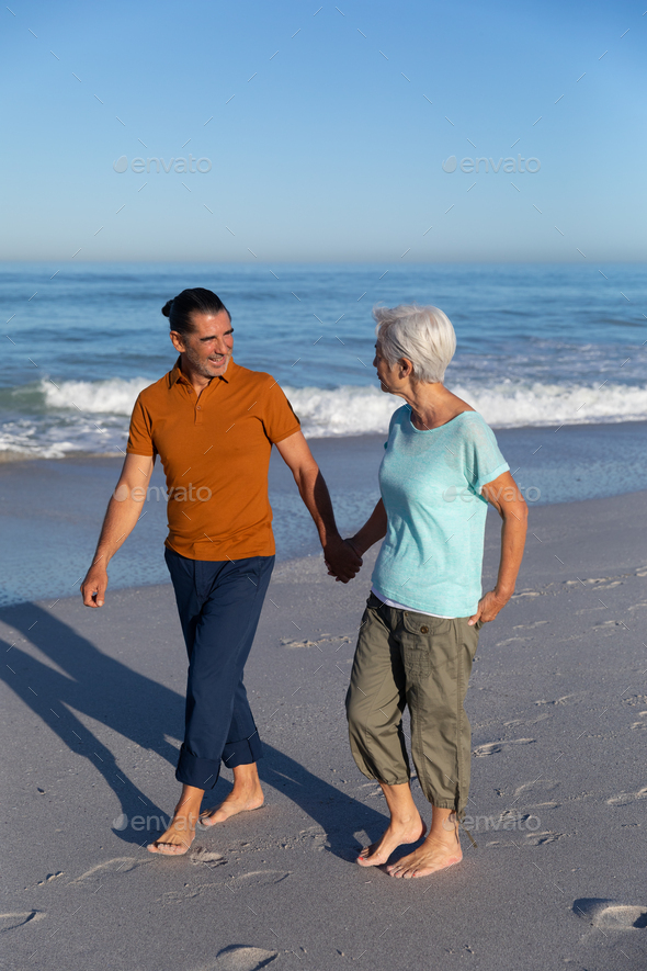 Senior Caucasian couple walking at the beach.
