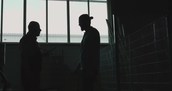 Silhouette of Two Engineers Talking and Shaking Hands at Industrial Factory alt