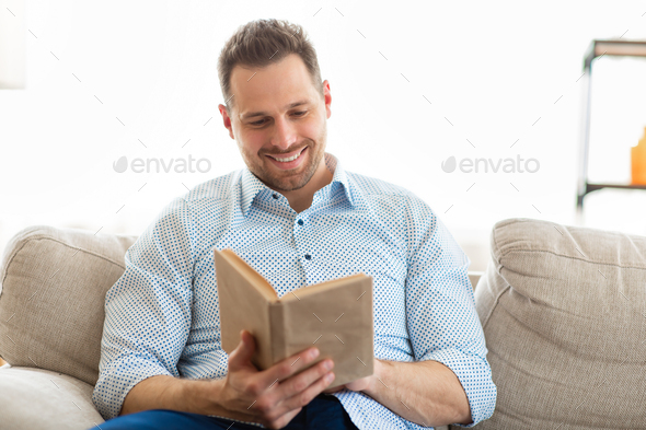 Handsome guy reading a book at home