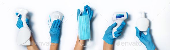 Raised hands in medical gloves holding masks, sanitizers, soap, non contact thermometer on white