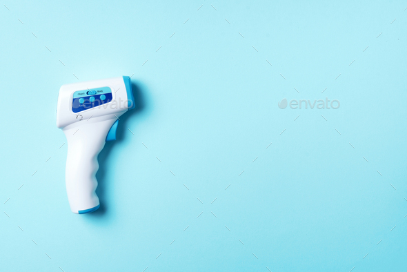 Digital medical infrared non contact thermometer gun for measuring temperature on blue background