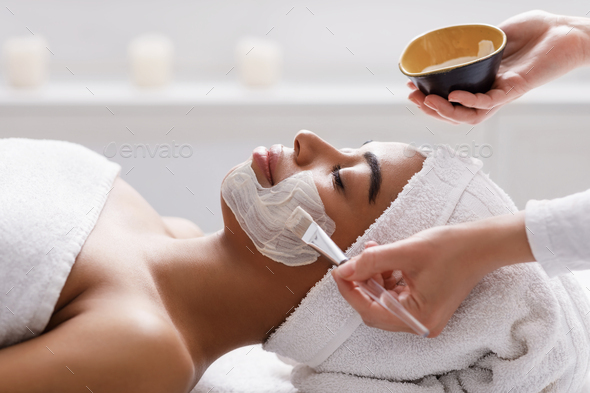 Beautician Applying Clay Face Mask On Woman Face