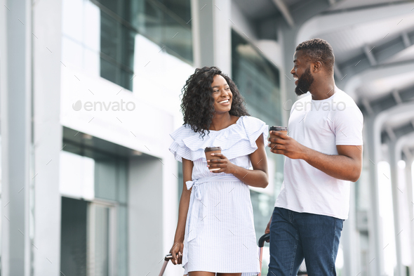 Happy Black Man And Woman Walking With Coffee Near Airport Building