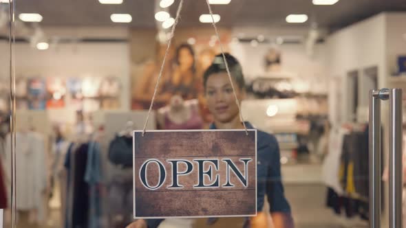 Young African American Woman Turning a Sign From Open to Closed on the Door of a Women's Brand alt