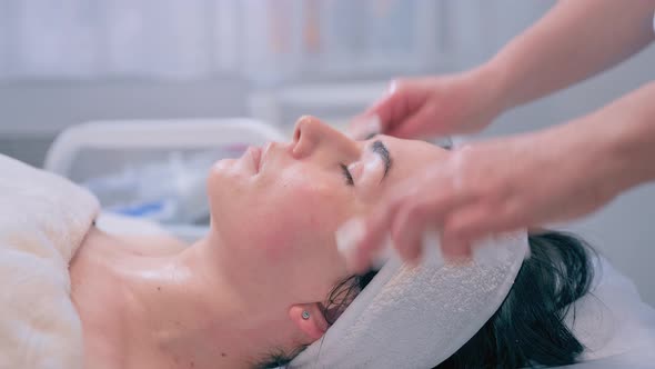 Cosmetologist Performs the Procedure of Cleansing and Moisturizing the Skin alt