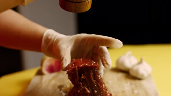 Male Tattooed Chef s Hand Seasoning Fresh Steak in a Bright Light alt