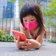 Asian child wearing mask and using cell phone in city - PhotoDune Item for Sale
