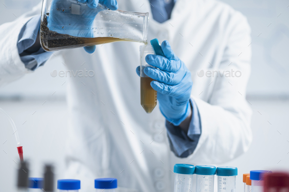 Organic Food Science Inspector Examining Laboratory Flask with Plant Sample Dissolved in Water