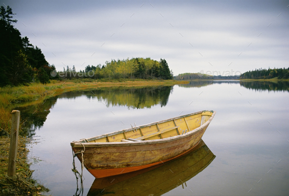 Small wooden dory or rowing boat moored on calm water, Savage harbor on Prince Edward Island Canada