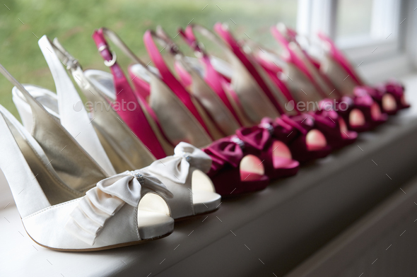 A row of high heeled shoes. Pairs of peep toe slingbacks in white and pink. Special occasion.