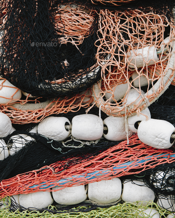 Pile of commercial fishing nets, with white floats, on the quayside