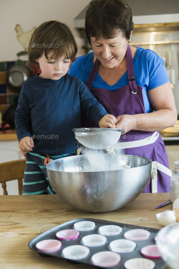 A woman and a child cooking at a kitchen table, making fairy cakes.