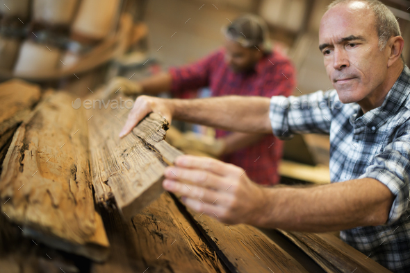A reclaimed lumber workshop, man measuring and checking planks of wood for re-use and recycling