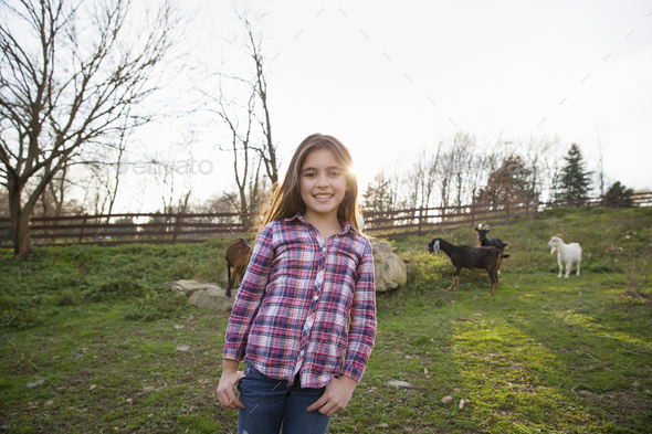 A child, a young girl in the goat paddock enclosure at an animal sanctuary.