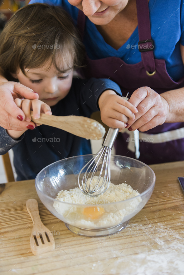 A woman and a child cooking at a kitchen table, making fairy cakes. - Stock Photo - Images