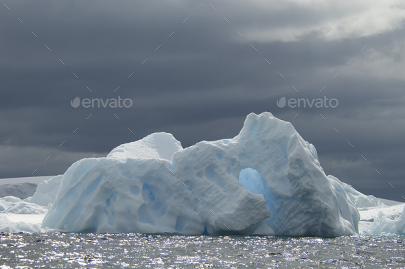 An iceberg on the waters of the Southern Ocean under a stormy grey sky.