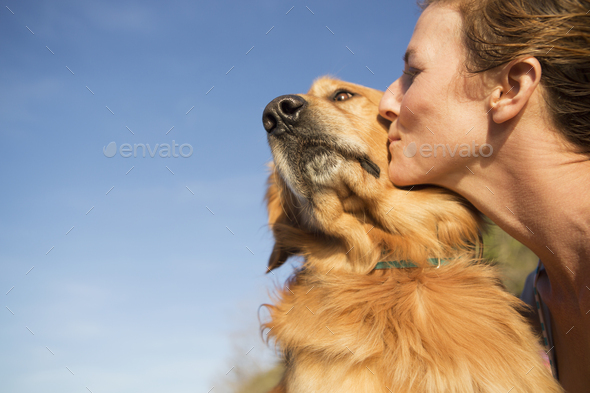 A woman kissing a pet dog on the cheek. - Stock Photo - Images