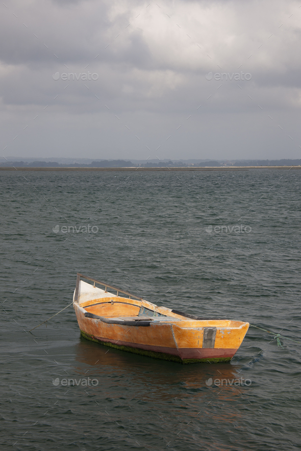 A small wooden boat moored in open water, off the Portuguese coast. Stock  Photo by Mint_Images