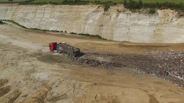 A landfill lorry is unloading garbage into junkyard. Aerial shot
