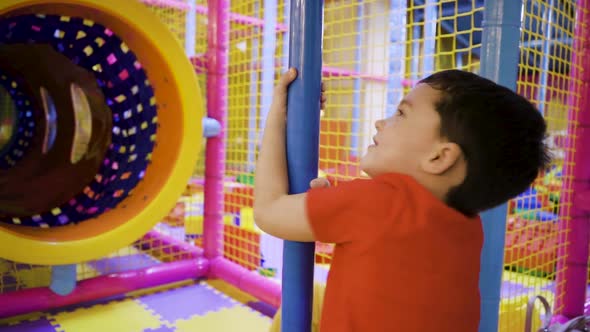 A Little Boy Spins Around a Pipe in an Amusement Park