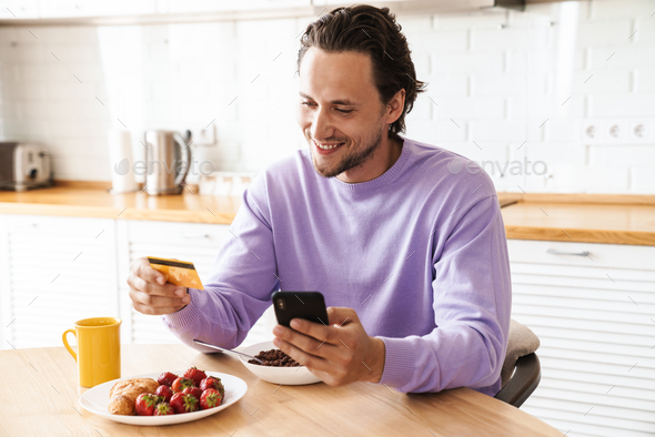 Attractive young man sitting at the kitchen table