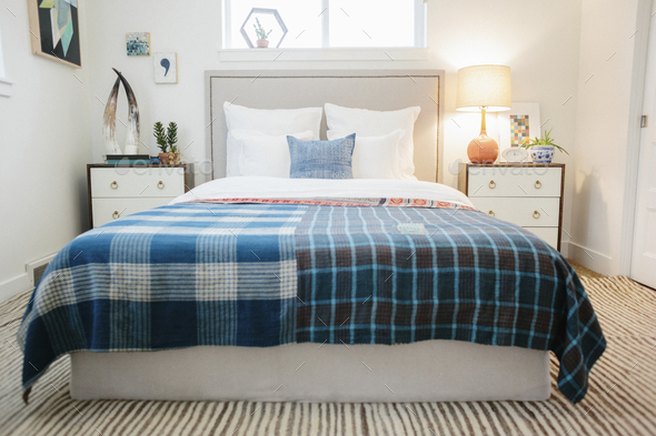 A bedroom in an apartment with a double bed with a colourful checked bed cover