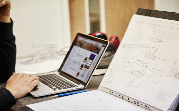 Furniture designer with sketches and laptop