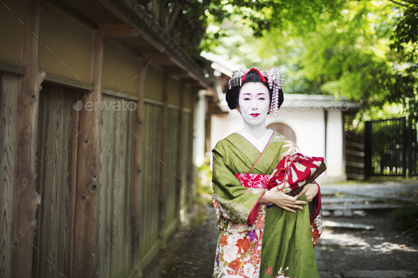 A woman dressed in the traeditional geisha style, wearing a kimono and obi,  with an elaborate Stock Photo by Mint_Images