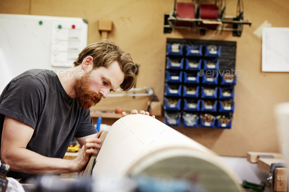 A man in furniture workshop working on a curved wooden piece of furniture. - Stock Photo - Images