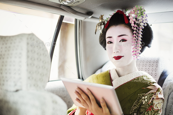 A traditional geisha wearing a kimono holding a digital tablet