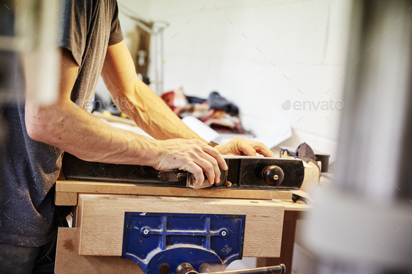 A man holding a piece of wood in a furniture workshop making bespoke contemporary furniture. - Stock Photo - Images
