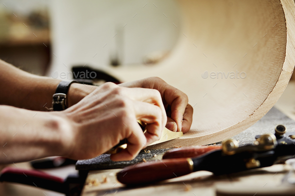 A man in a furniture workshop working on a piece of curved wood. - Stock Photo - Images