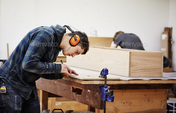 A man marking a piece of wood with a pencil. - Stock Photo - Images