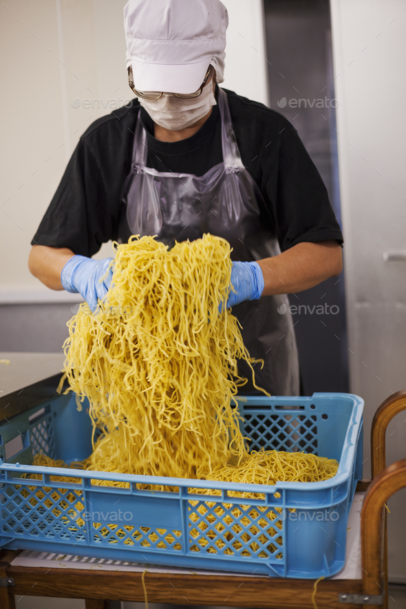 Workers collecting freshly cut noodles from the conveyor belt to