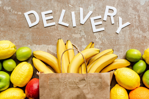 Top View of Word Delivery Near Paper Bag With Colorful Fresh Fruits on Beige Weathered Surface