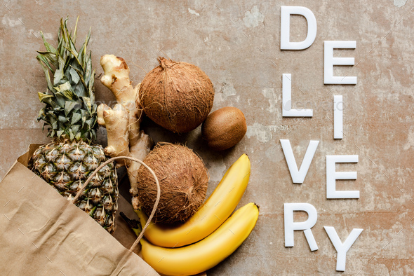 Tropical Fresh Fruits And Ginger Root in Paper Bag on Weathered Surface With Word Delivery