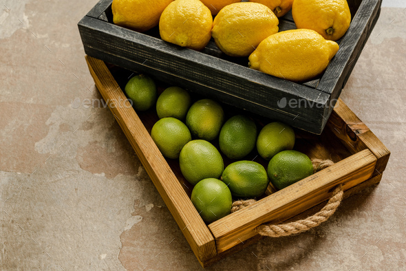 Ripe Lemons And Limes in Wooden Boxes on Weathered Surface