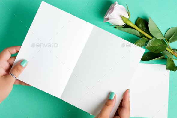 Woman's hands are holding empty mock-up paper sheet for writing letter above pastel turquoise - Stock Photo - Images